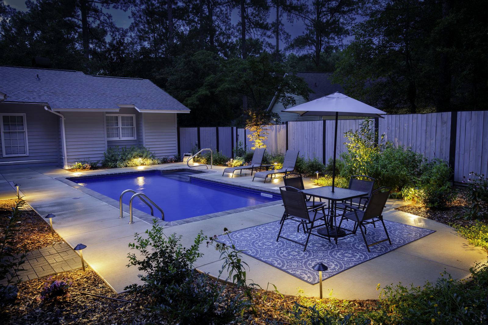 Backyard pool and patio outdoor living space at dusk